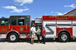 Joey Creech, Kelly Aycock, and Karen Jones holding check and standing in front of new fire truck.